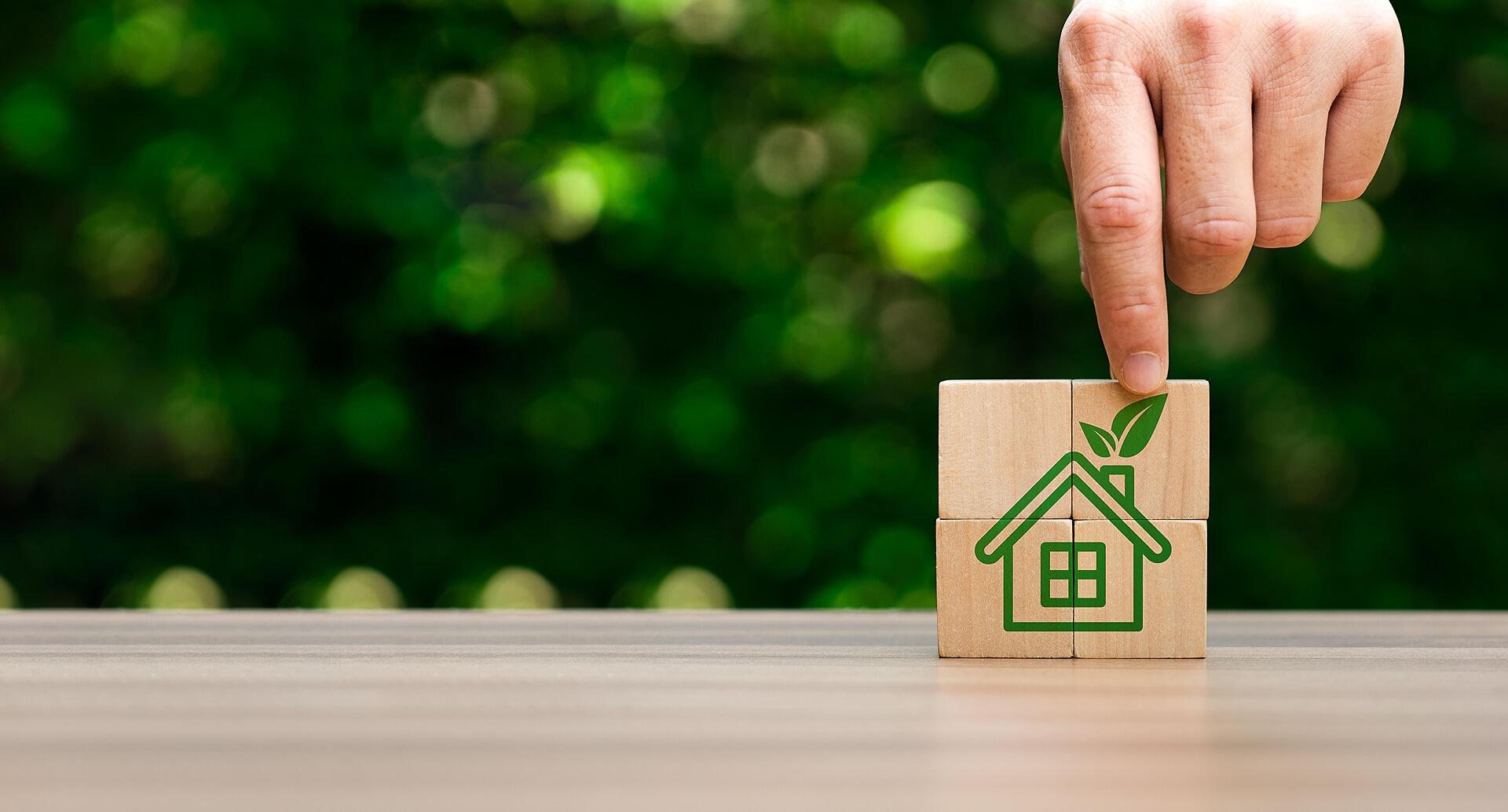 Hand putting together building blocks that depict an energy efficient house